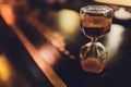 Hourglass with falling sand inside a glass bulb, passing time or lost time on a dark background with space for text.