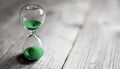 Hourglass with green sand time passing background concept for business deadline, urgency and running out of time Royalty Free Stock Photo