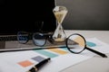 Hourglass, laptop and reports on a desk, business and time management concept Royalty Free Stock Photo