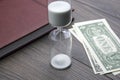 Hourglass, money and notebook are on the table. Business office items. Time is money. Business solutions in time
