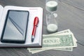 the a Hourglass, money, pen and notebook are on the table. Business office items. Time is money. Business solutions in time