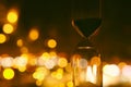 Hourglass over bokeh city lights as time passing concept for business deadline.