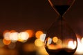 Hourglass over bokeh city lights as time passing concept for business deadline.