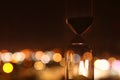 Hourglass over bokeh city lights as time passing concept for business deadline.