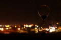 Hourglass over bokeh city lights as time passing concept for business deadline.