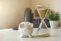 Hourglass with piggy bank on the background with a phone, concept of losing money, outgoing money