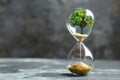 Hourglass with planet earth and tree inside on grey background, concept of time for environmental protection and climate change. Royalty Free Stock Photo