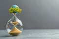 Hourglass with planet earth and tree inside on grey background, concept of time for environmental protection and climate change. Royalty Free Stock Photo