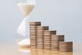 Hourglass red sand and stack of coins. Royalty Free Stock Photo