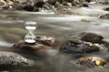 A hourglass on a rock of a creek. Royalty Free Stock Photo