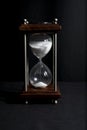 Hourglass, or sand clock isolated in black background, in low li