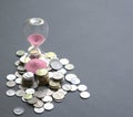 Hourglass with sand flowing and coins on table Royalty Free Stock Photo