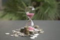 Hourglass with sand flowing and coins on table Royalty Free Stock Photo