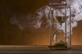 Hourglass and smoke on a wooden table Royalty Free Stock Photo