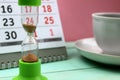Hourglass stand on the background of a calendar and a cup of coffee