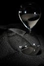 Hourglass stand on black sand with silhouette shadow over black background. Black hourglass show more time Deadline extended time Royalty Free Stock Photo