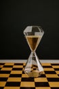 Hourglass stands on a chessboard. Leadership and management strategy concept. Vertical image