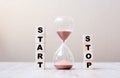 Hourglass with START and STOP wooden cube blocks on table, Sand flowing through the bulb of Sandglass measuring the passing time.