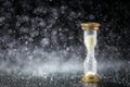 Hourglass under the water drops on black background. Time limited. Deadline. Marketing strategy.