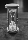 Hourglass on wooden table, dark background. Sand falling down inside of hourglass. Time flow concept. Wooden hourglass Royalty Free Stock Photo