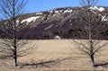 The house is between the bare trees in Iceland