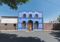 House with a blue facade, traditional Mexican architecture, with a man walking down the street.