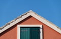The house on the blue sky background. Roof and window with shutters. Architectural composition.