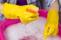 House cleaning. Close-up of basin with soapy water, hands in protective rubber gloves with sponge.