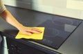 House cleaning concept - woman holding dry microfiber rag wiping the glass surface induction cooker and kitchen countertop from Royalty Free Stock Photo