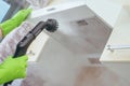 House cleaning. Girl brushes steam cleaners kitchen drawing with steam in green gloves. cleaning of a surface