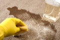 House cleaning and scrubbing the floor concept with close up of a hand wearing yellow rubber gloves cleaning up a spilled cup of Royalty Free Stock Photo