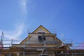 House construction - The roof ridge of the new building stretches behind the scaffolding into the blue sky