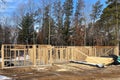 House construction site with wall studs and stacks of wood lumber