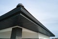 House corner with brown metal planks siding and roof with steel gutter rain system. Roofing, construction, drainage