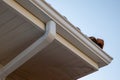 House corner with white wooden planks siding and roof with steel gutter rain aluminum system drainage pipes installation