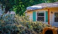 House with damaged roof with plastic covering it and tree that fell on it piled up in foreground - storm aftermath Royalty Free Stock Photo