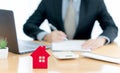 A House on desk envelope with man signing purchase documents in background. while hand complete the insurance policy, rental