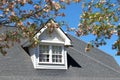 House with a dormer in its roof stands beneath a clear blue sky on a sunny day