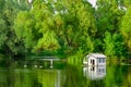 house for ducks and swans on lake surrounded by trees. bird house on pond on summer day in city park Royalty Free Stock Photo