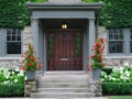 House with elegant wood grain door, surrounded by ivy and red amaryllis