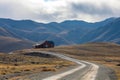 house at the end of a long, winding road, mountains behind Royalty Free Stock Photo