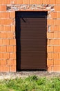 House entrance doors completely closed with new dark brown rollup window blinds mounted on unfinished red brick wall Royalty Free Stock Photo