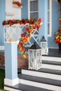 House entrance staircase decorated for autumn holidays, fall flowers and pumpkins. Cozy porch of the house with wooden lanterns in