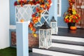 House entrance staircase decorated for autumn holidays, fall flowers and pumpkins. Cozy porch of the house with wooden lanterns in