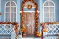 House entrance staircase decorated for autumn holidays, fall flowers and pumpkins. Cozy wooden porch of the house with pumpkins Royalty Free Stock Photo