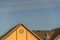 House exterior with roof shingles and round gable window against blue sky Royalty Free Stock Photo