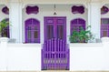 house exterior with white walls and purple windows, door and fence. cozy house is behind fence. Royalty Free Stock Photo