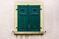 House facade with green closed wooden shutter with 4 oval light openings