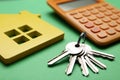 House figure with calculator and keys on background, closeup. Real estate agent service