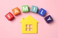 House figure and word Family made of colorful cubes with letters on pink table, flat lay Royalty Free Stock Photo